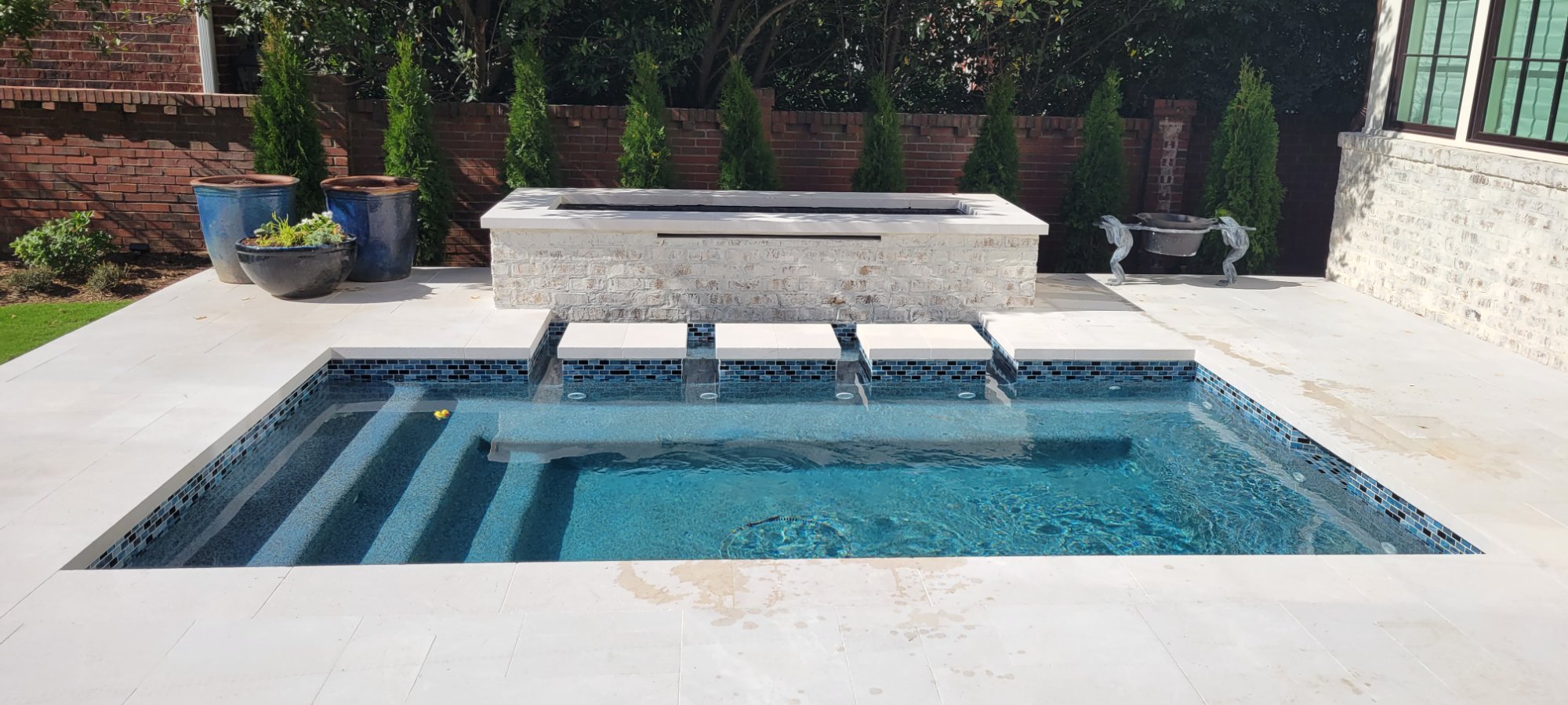 Edgewater Pools custom spool with fire bar and travertine steppers